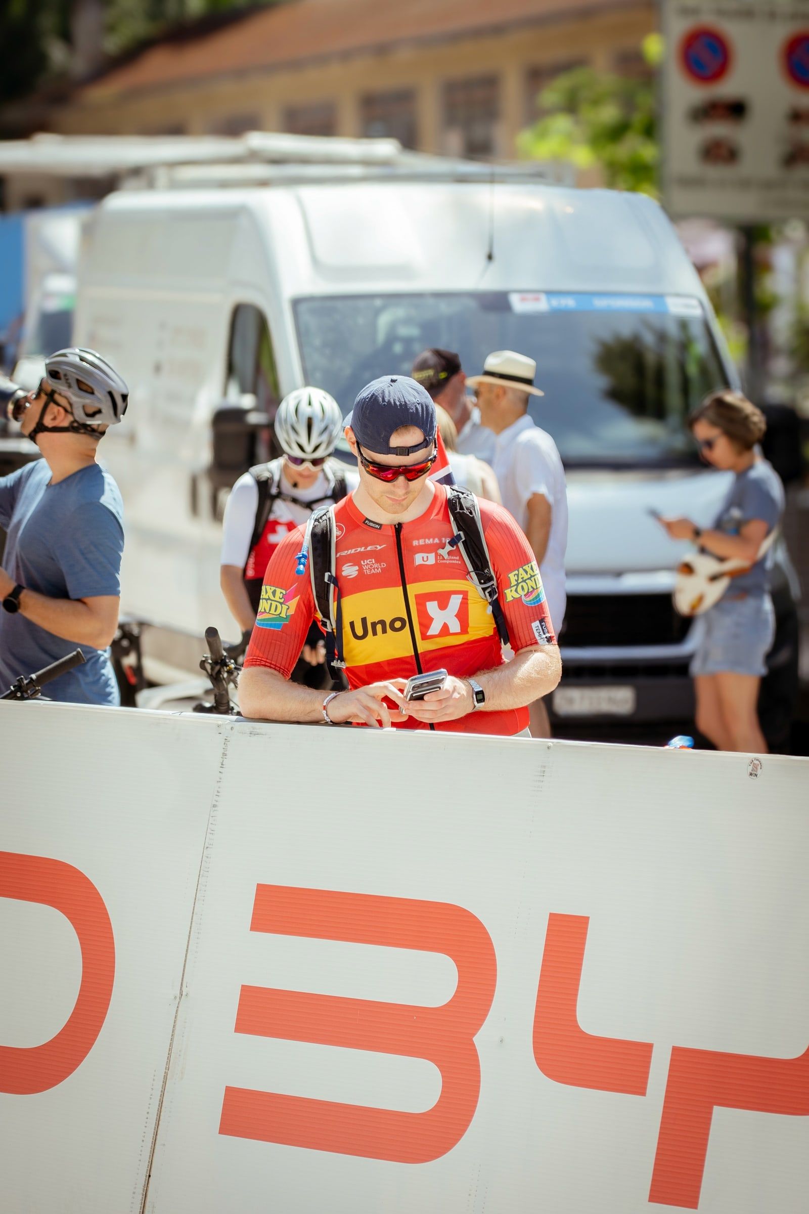 Rennfahrer mit Mütze wartet hinter der Absperrung